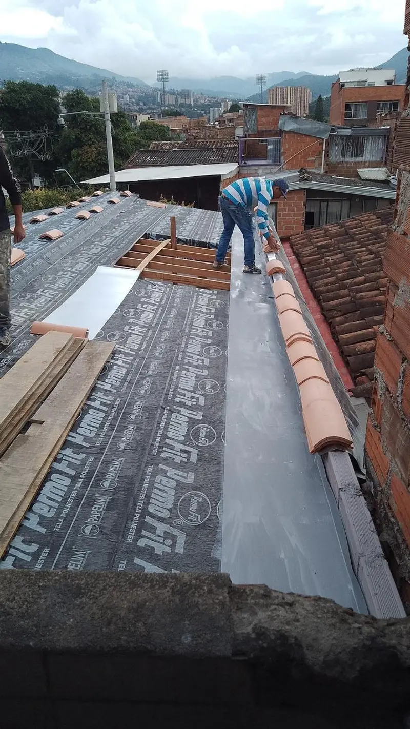 Plomero instalando manto impermeabilizante sobre la cubierta de una casa en Medellín